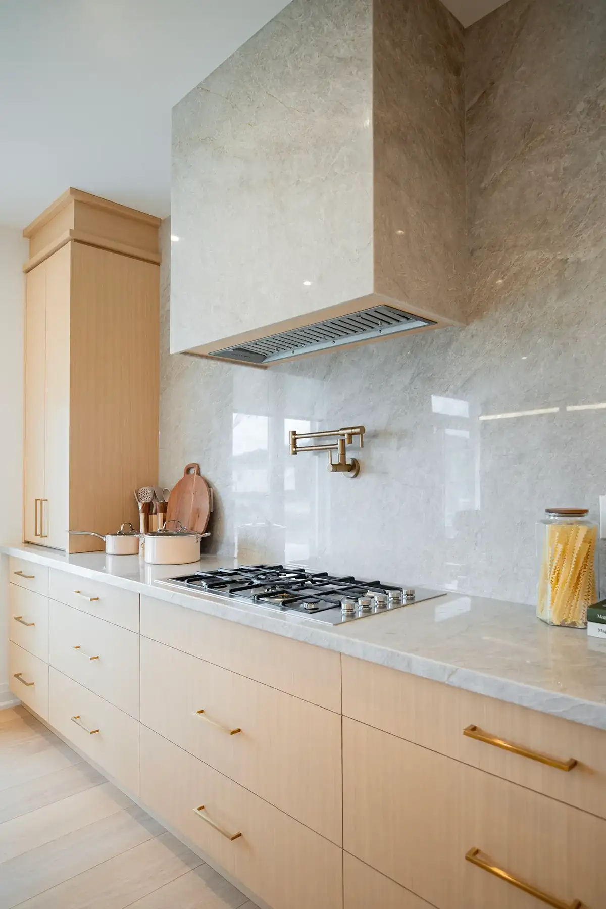 Kitchen interior with a panelled range hood and pale cabinetry